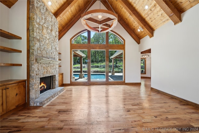 unfurnished living room with beam ceiling, light hardwood / wood-style floors, a stone fireplace, and high vaulted ceiling