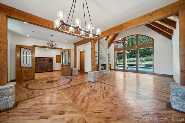 interior space with high vaulted ceiling, beam ceiling, a chandelier, and a fireplace