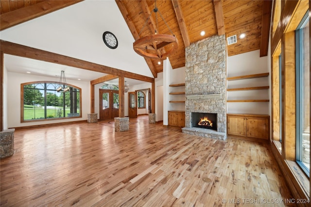 unfurnished living room featuring light hardwood / wood-style floors, beam ceiling, a stone fireplace, high vaulted ceiling, and wooden ceiling