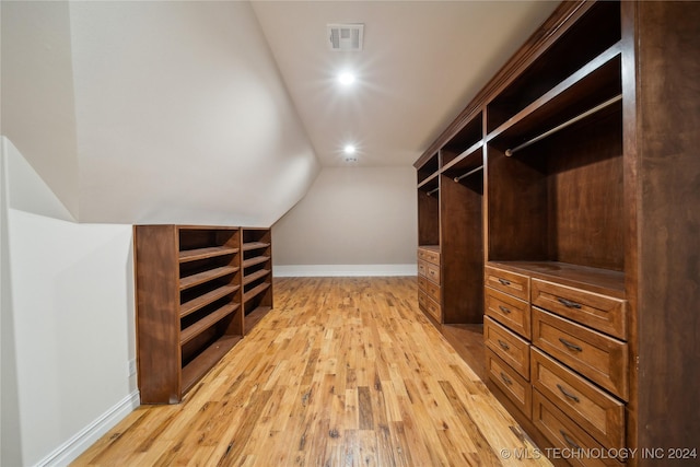 walk in closet with vaulted ceiling and light hardwood / wood-style floors