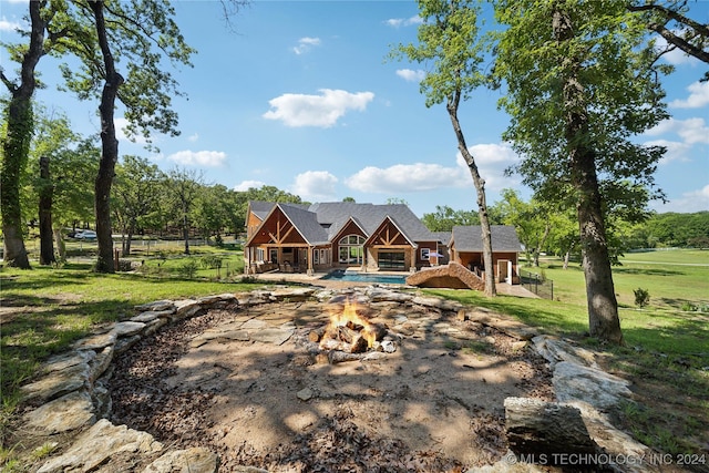 back of property with a lawn and an outdoor fire pit