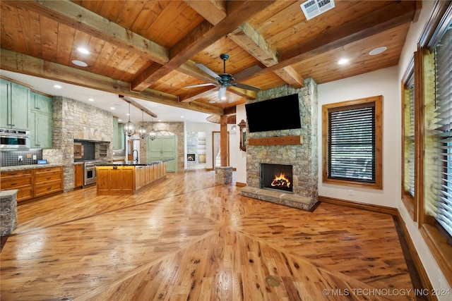 living room with a fireplace, beamed ceiling, sink, ceiling fan with notable chandelier, and wooden ceiling