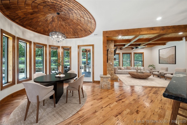 dining area with light wood-type flooring, ceiling fan with notable chandelier, and beamed ceiling