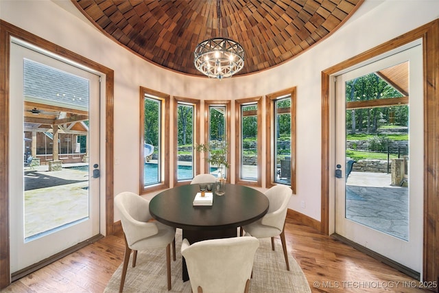 dining space featuring brick ceiling, light hardwood / wood-style floors, a notable chandelier, french doors, and vaulted ceiling