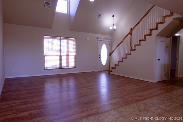 foyer entrance with hardwood / wood-style floors, a notable chandelier, and a high ceiling