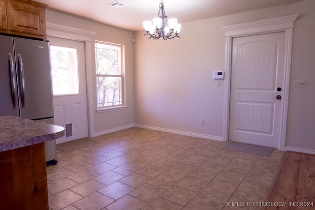 unfurnished dining area with an inviting chandelier