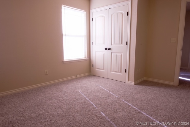 unfurnished bedroom with light colored carpet and a closet