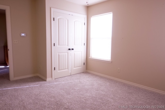 unfurnished bedroom with a closet and light colored carpet