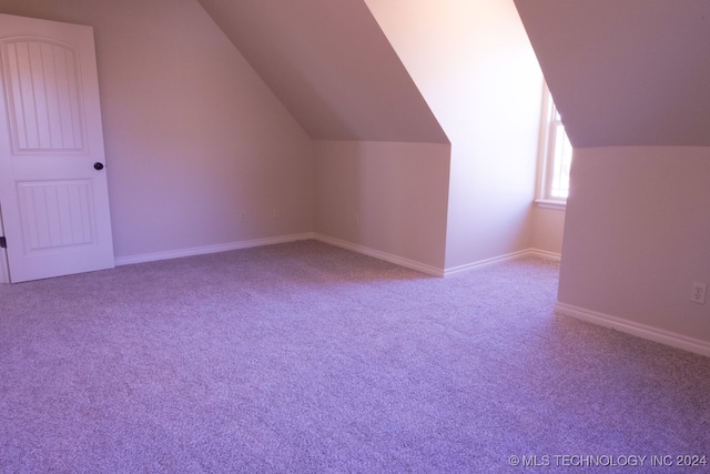 bonus room with light colored carpet and vaulted ceiling