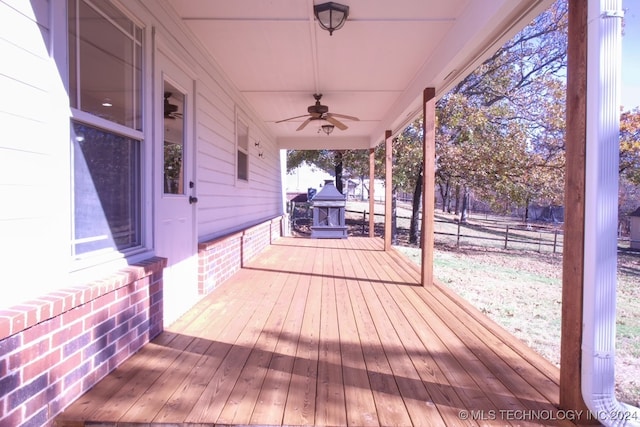 wooden deck featuring an outdoor brick fireplace and ceiling fan