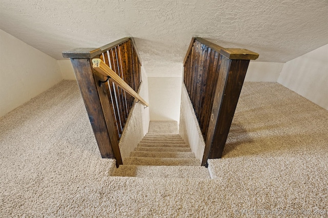 staircase featuring carpet floors and a textured ceiling