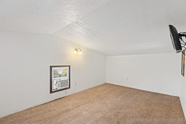 spare room with carpet, a textured ceiling, cooling unit, and lofted ceiling