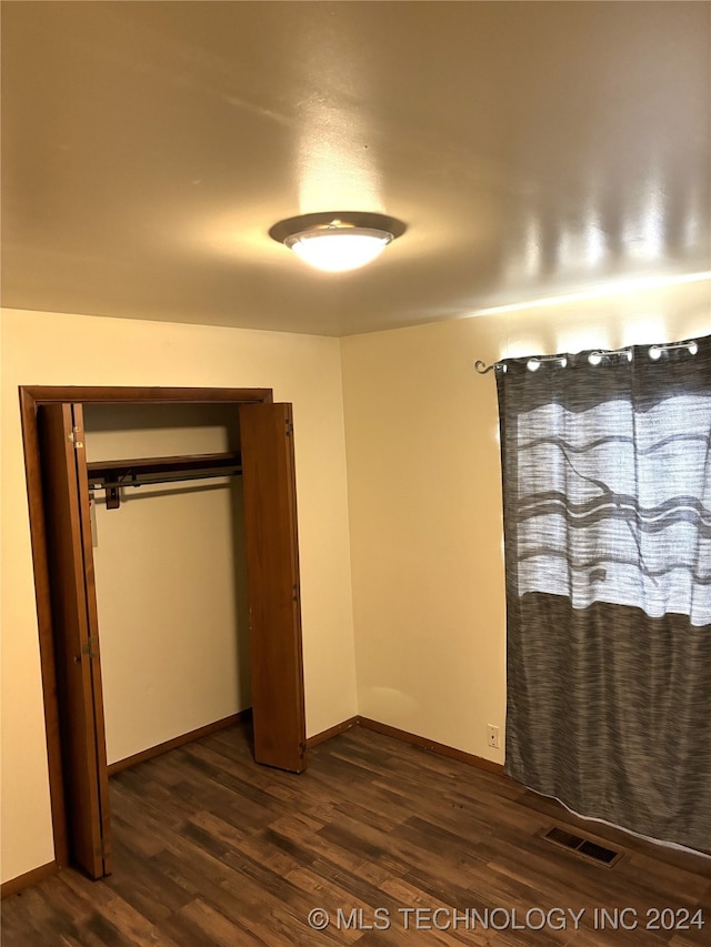 unfurnished bedroom featuring dark hardwood / wood-style flooring and a closet