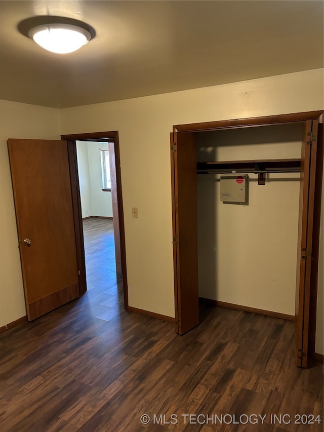 unfurnished bedroom featuring a closet and dark wood-type flooring