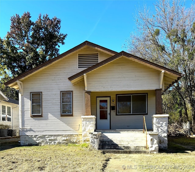 bungalow-style house featuring covered porch and a front lawn