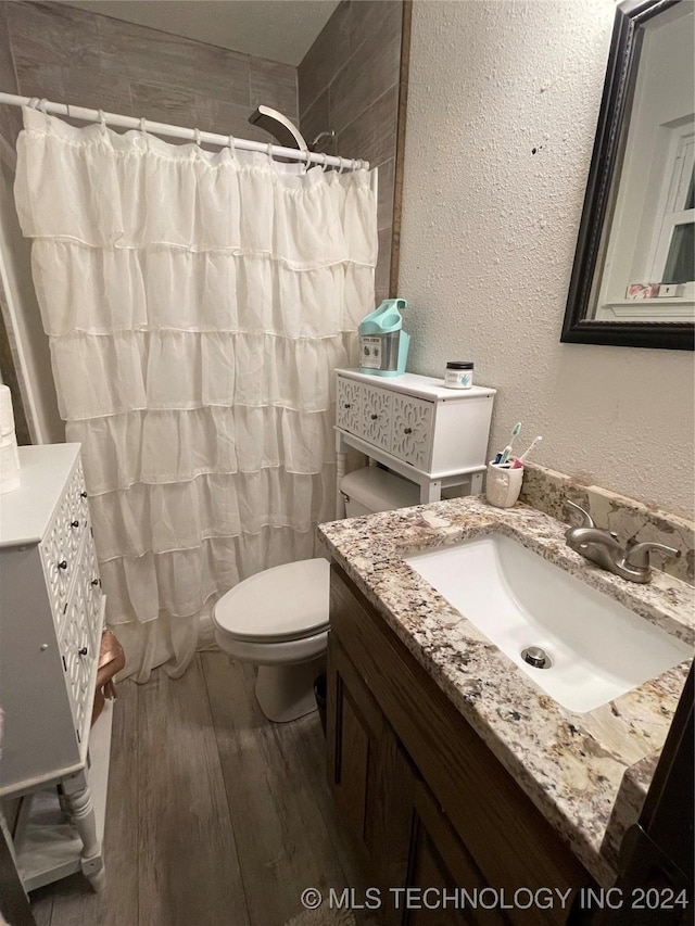 bathroom featuring walk in shower, hardwood / wood-style floors, vanity, and toilet