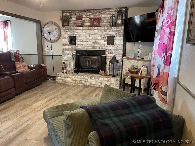 living room with a brick fireplace and light hardwood / wood-style flooring