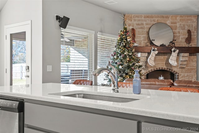 kitchen featuring light stone countertops, a stone fireplace, a wealth of natural light, and sink