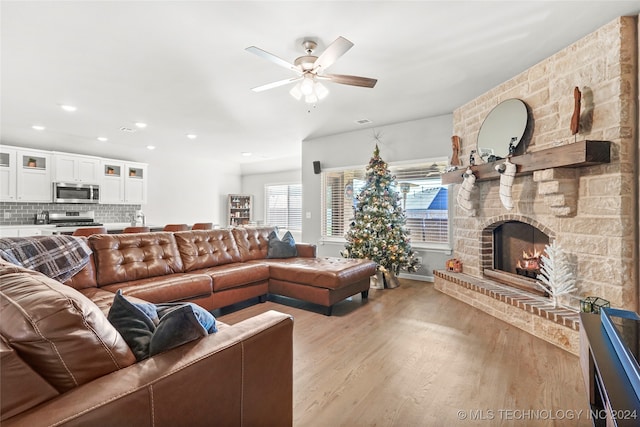 living room featuring ceiling fan, light wood-type flooring, and a fireplace