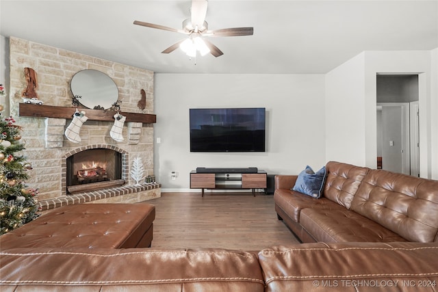 living room featuring hardwood / wood-style floors, a stone fireplace, and ceiling fan