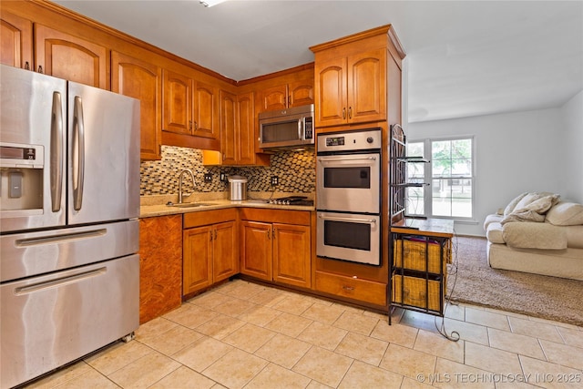 47 S 204th E Ave, Tulsa, OK 74108 - kitchen featuring appliances with stainless steel finishes, backsplash, brown cabinetry, and light tile patterned floors