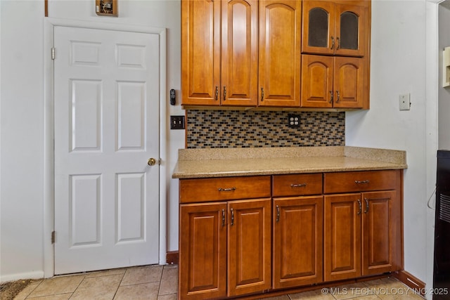 47 S 204th E Ave, Tulsa, OK 74108 - kitchen with backsplash, brown cabinets, glass insert cabinets, and light stone counters