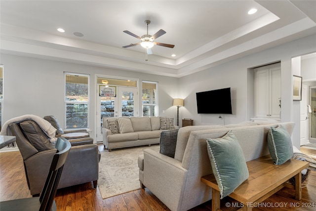 living room with dark hardwood / wood-style flooring, ceiling fan, a raised ceiling, and french doors