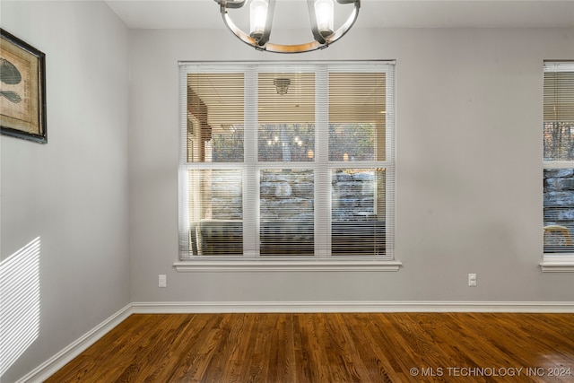 unfurnished room featuring hardwood / wood-style flooring and a chandelier