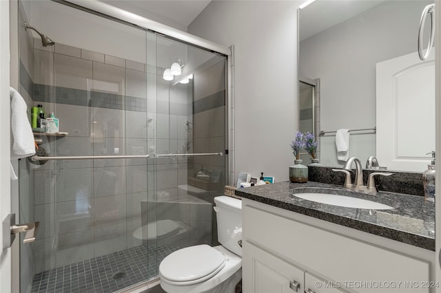 bathroom featuring vanity, toilet, and a shower with door