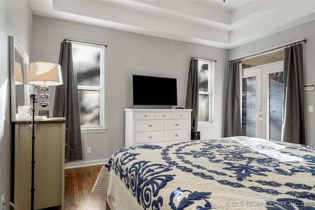 bedroom featuring a tray ceiling, access to exterior, french doors, and dark wood-type flooring