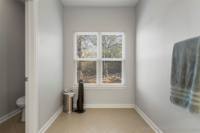 bathroom with tile patterned flooring, toilet, and a healthy amount of sunlight