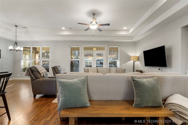 living room with ceiling fan with notable chandelier, a raised ceiling, wood-type flooring, and french doors