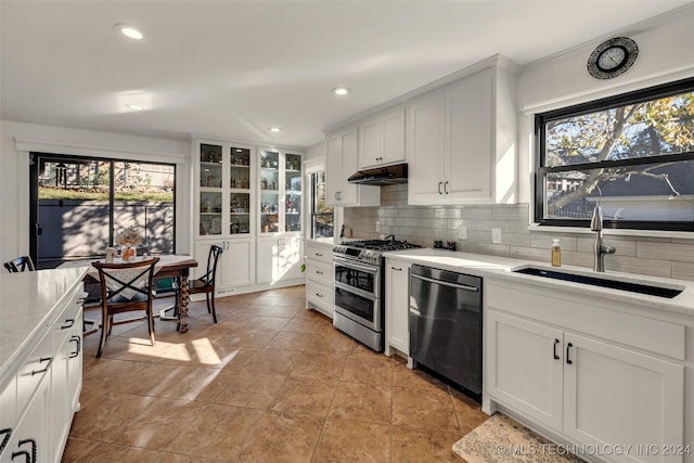 kitchen with range with two ovens, dishwasher, backsplash, white cabinetry, and sink