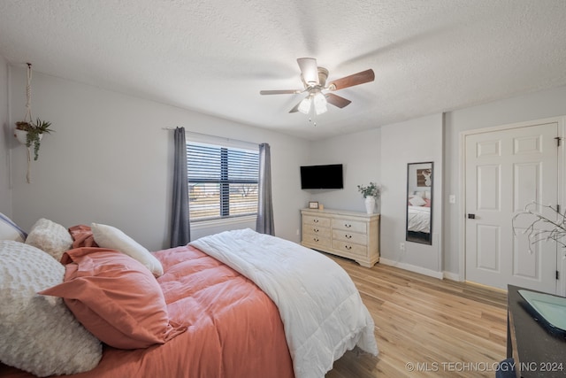 bedroom with ceiling fan, light hardwood / wood-style floors, and a textured ceiling