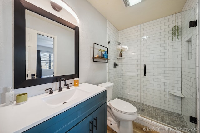 bathroom with vanity, toilet, a shower with door, and hardwood / wood-style flooring