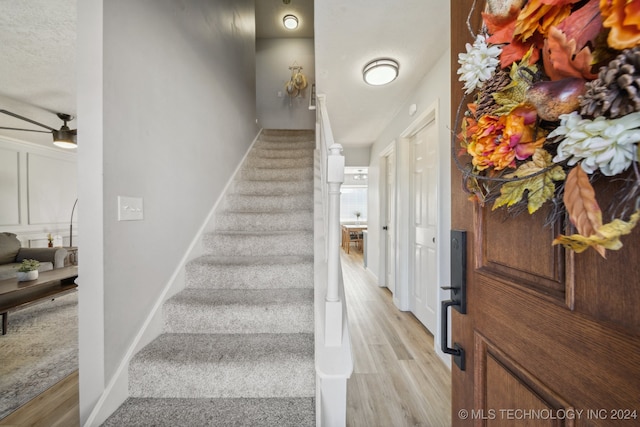 stairs featuring hardwood / wood-style floors and ceiling fan