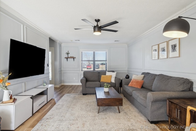 living room with crown molding, light wood-type flooring, a textured ceiling, and ceiling fan