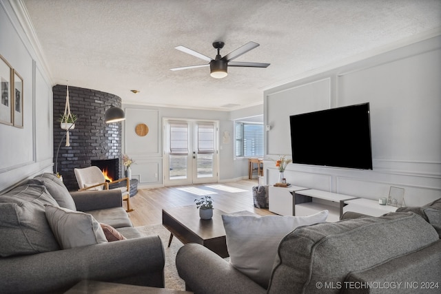 living room with a textured ceiling, light wood-type flooring, ornamental molding, and a fireplace