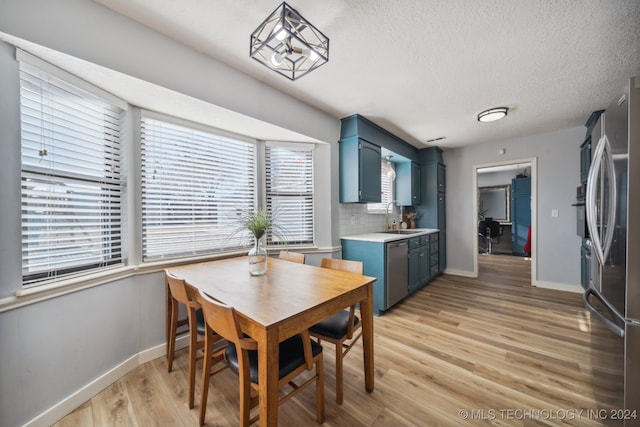 dining room with sink, light hardwood / wood-style flooring, and a textured ceiling