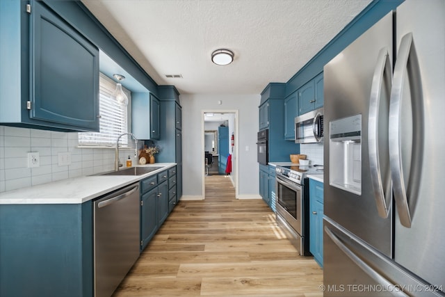 kitchen with blue cabinetry, appliances with stainless steel finishes, and sink