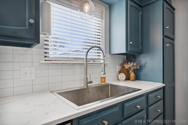 kitchen featuring sink, tasteful backsplash, and blue cabinets