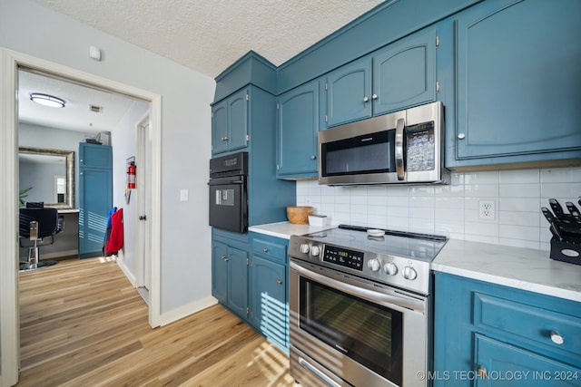 kitchen with blue cabinetry, a textured ceiling, and appliances with stainless steel finishes