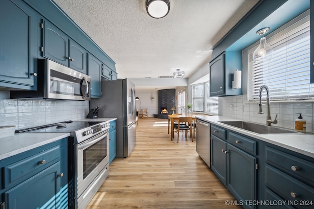 kitchen featuring sink, stainless steel appliances, blue cabinets, and pendant lighting