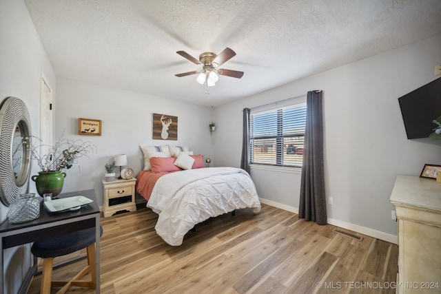 bedroom featuring ceiling fan, a textured ceiling, and wood-type flooring