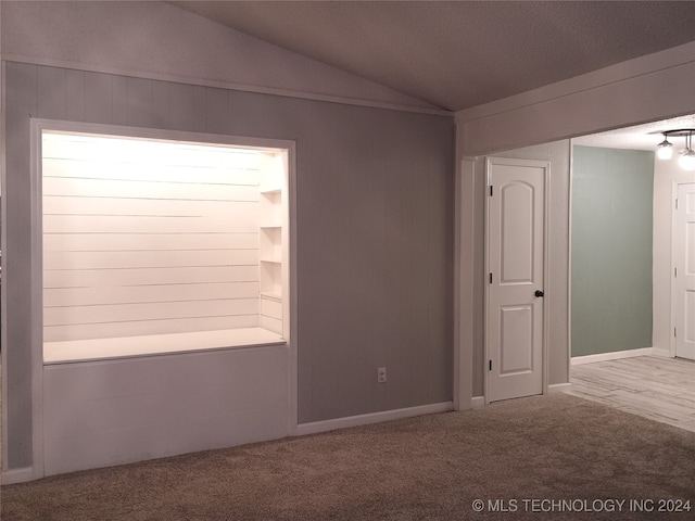 carpeted spare room featuring a textured ceiling and lofted ceiling