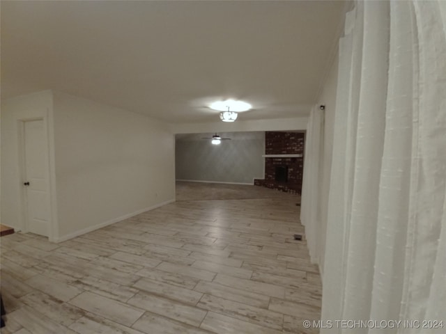 spare room with light wood-type flooring and a brick fireplace