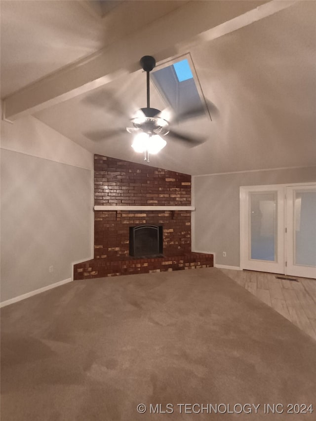 unfurnished living room featuring a fireplace, carpet, ceiling fan, and vaulted ceiling with skylight