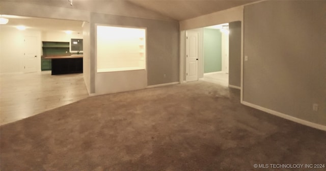 empty room with carpet floors and vaulted ceiling