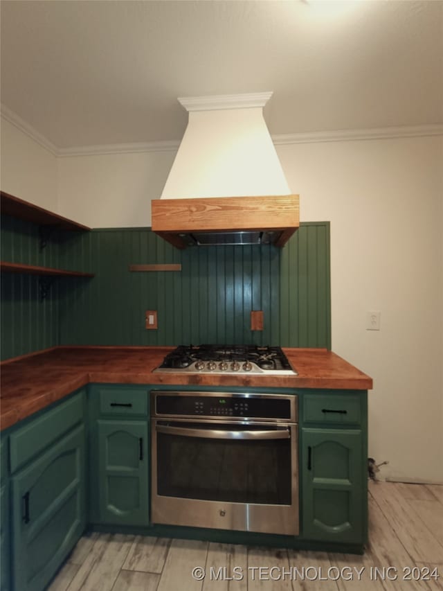 kitchen with stainless steel appliances, light hardwood / wood-style flooring, wooden counters, crown molding, and custom exhaust hood