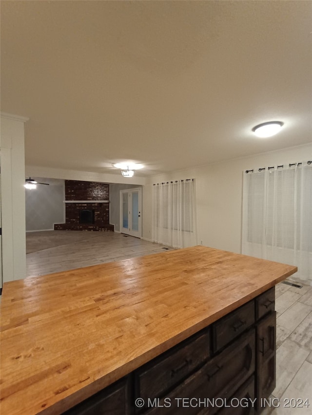 kitchen featuring a fireplace, dark brown cabinets, and light hardwood / wood-style flooring